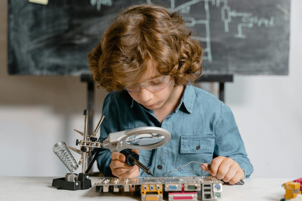 pexels-photo-8471939-8471939 Young boy diligently working on a circuit board, exploring science and technology.